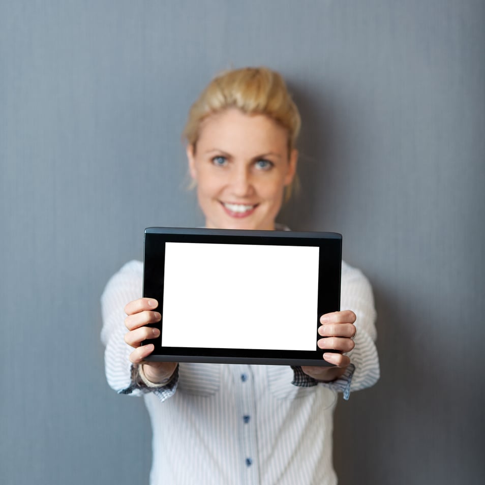 Portrait of a smiling young businesswoman presenting digital tablet against gray background