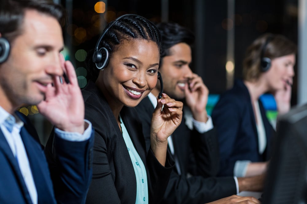 Portrait of businesswoman with headsets using computer at office desk